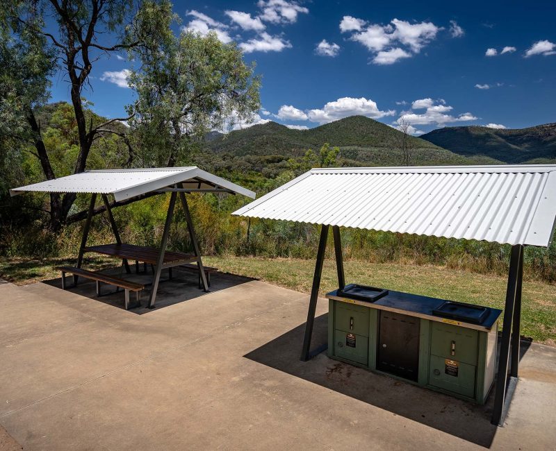 An outdoor picnic and barbecue (BBQ) area in a scenic, hilly natural setting.