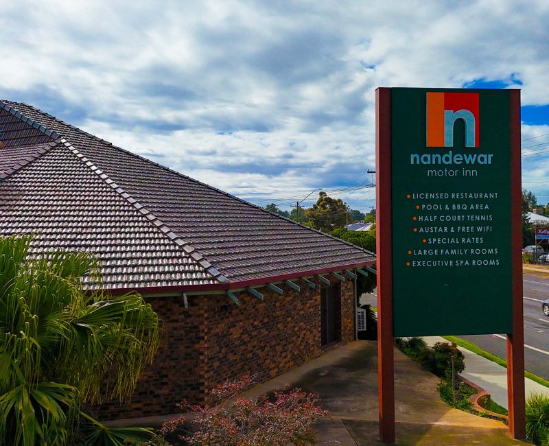 A low-angle, exterior view of Nandewar Motor Inn entrance and a prominent sign.