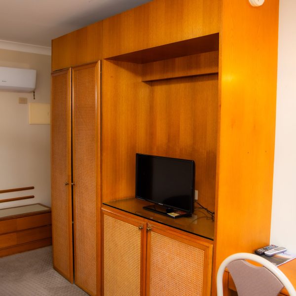 A large, built-in wooden cabinet unit with a honey-orange stain dominates the center of the image