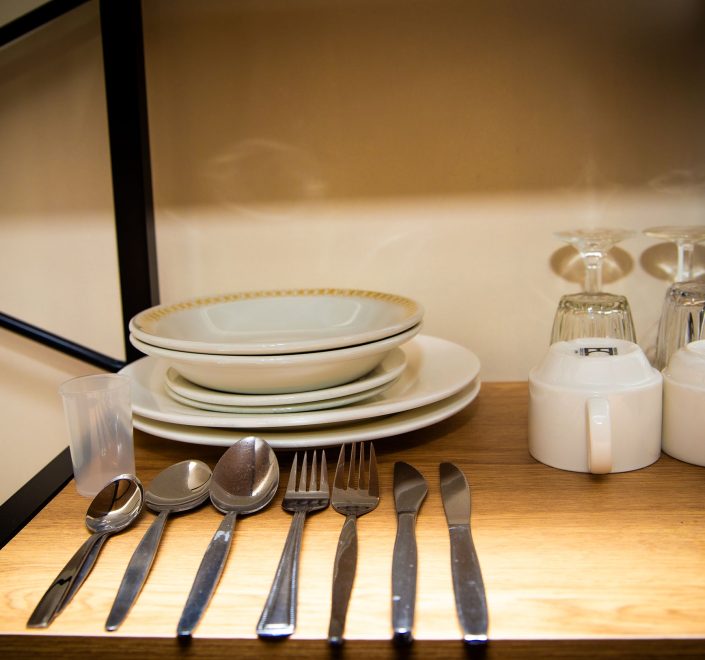 A close-up view of a wooden shelf with a black metal frame, displaying guest amenities.