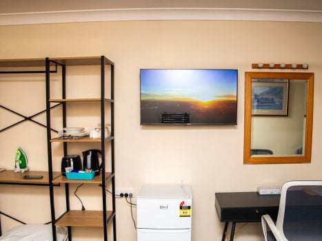 A section of Nandewar Motor Inn's room wall painted light beige, featuring various amenities.