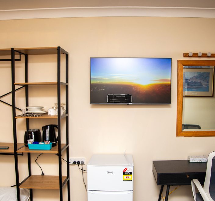 A section of Nandewar Motor Inn's room wall painted light beige, featuring various amenities.