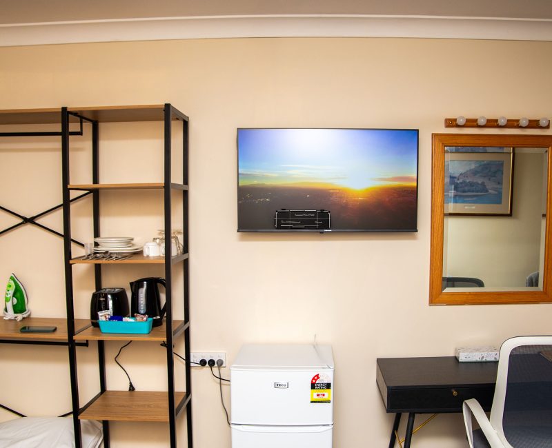 A section of Nandewar Motor Inn's room wall painted light beige, featuring various amenities.