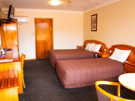 A view inside Nandewar Motor Inn room featuring two single or double beds with matching brown quilted bedspreads and white pillows.