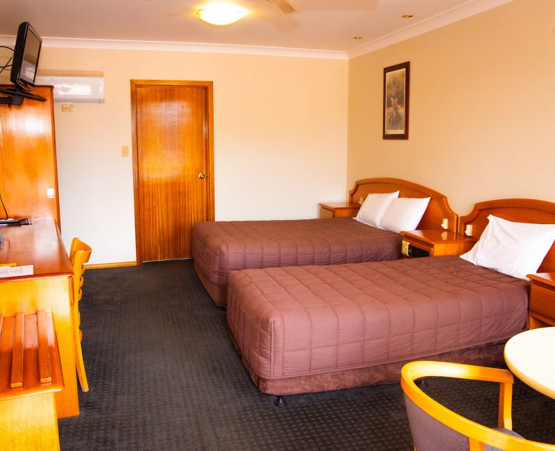 A view inside Nandewar Motor Inn room featuring two single or double beds with matching brown quilted bedspreads and white pillows.