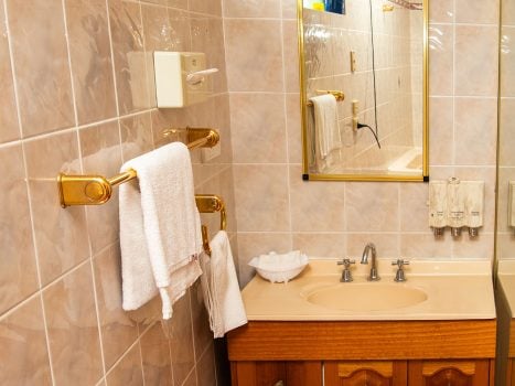 A bathroom featuring a wooden vanity cabinet with gold-toned drawer pulls and a light peach or beige countertop and integrated sink.