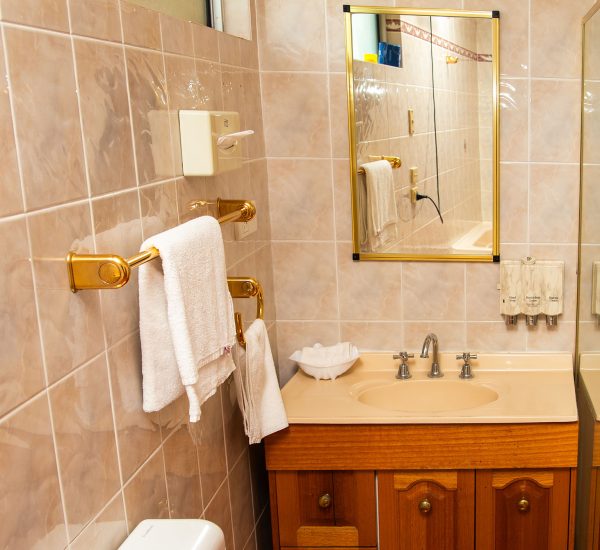 A bathroom featuring a wooden vanity cabinet with gold-toned drawer pulls and a light peach or beige countertop and integrated sink.