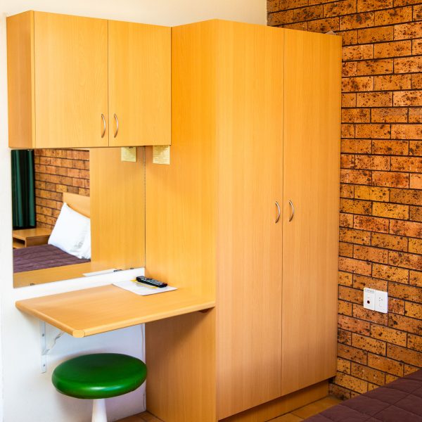 A tall, light-toned, wooden cabinet unit is built into the corner of the room.