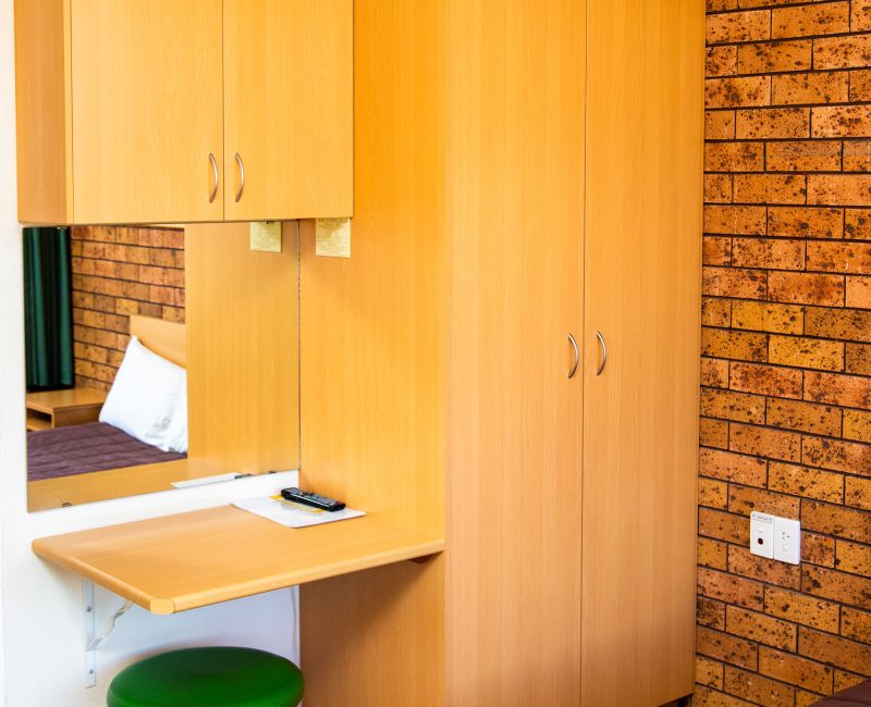 A tall, light-toned, wooden cabinet unit is built into the corner of the room.