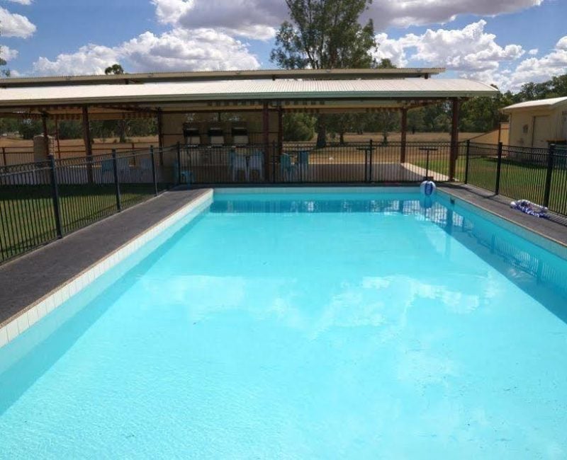 An outdoor swimming pool and adjacent covered amenity area.