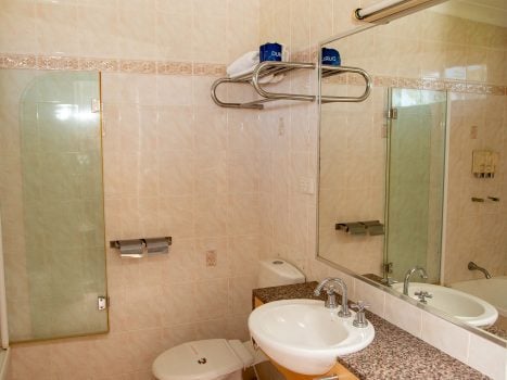 Nandewar Motor Inn's bathroom with walls tiled in large, light beige or pale pink marbled tiles.