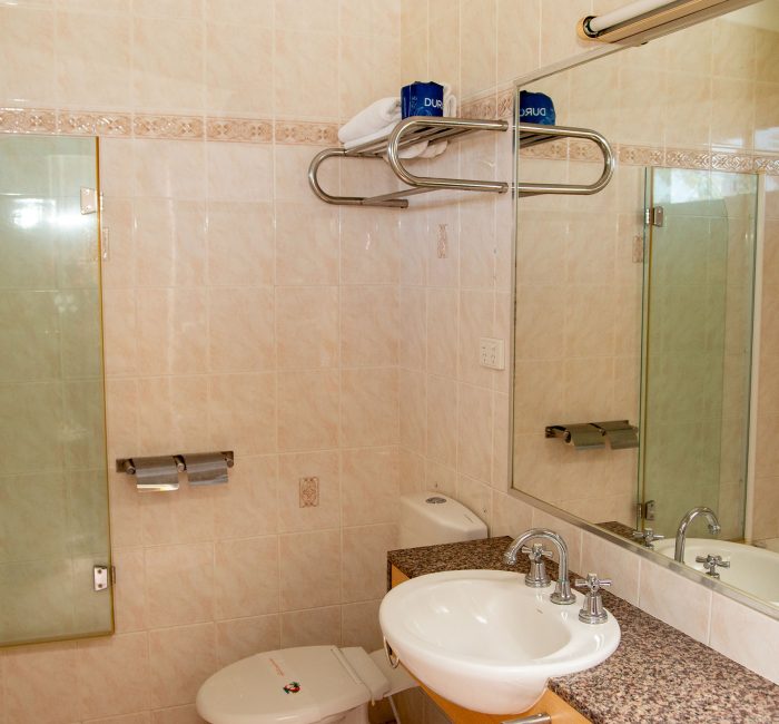 Nandewar Motor Inn's bathroom with walls tiled in large, light beige or pale pink marbled tiles.