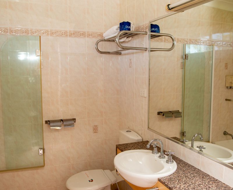 Nandewar Motor Inn's bathroom with walls tiled in large, light beige or pale pink marbled tiles.
