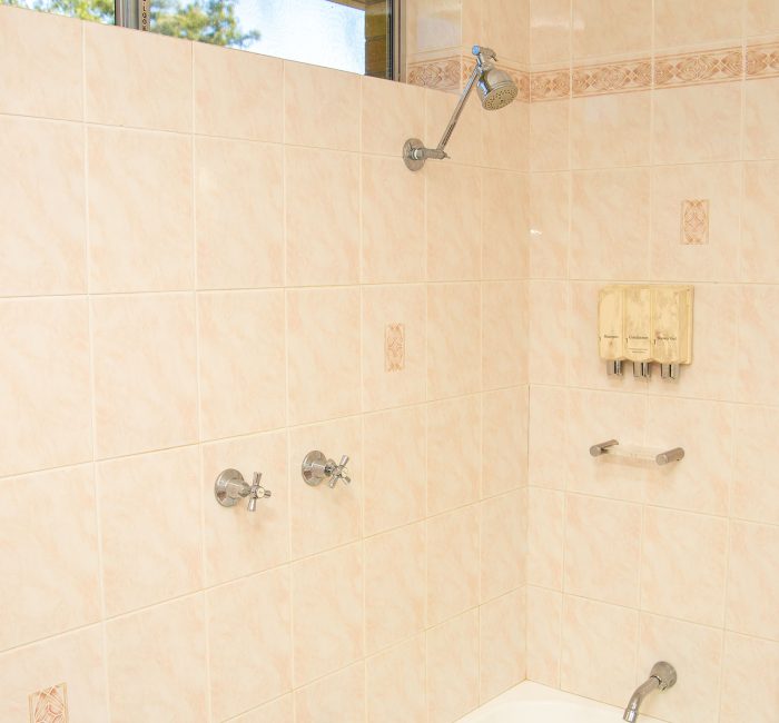 A bathroom area with walls covered in large, square, light beige or pale pink marbled tiles.
