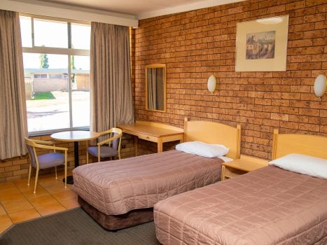 Nandewar Motor Inn room featuring two single beds with mauve or brownish-pink quilted comforters and light wood headboards.