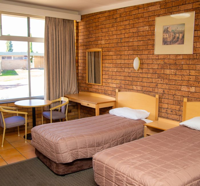 Nandewar Motor Inn room featuring two single beds with mauve or brownish-pink quilted comforters and light wood headboards.