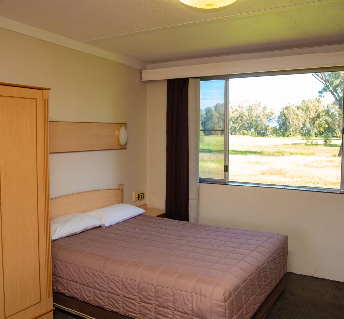 Nandewar Motor Inn's room featuring a double or queen-sized bed with a dusty-rose or mauve quilted comforter and white pillows.