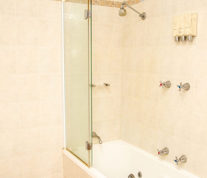 A close-up of a combined tub and shower area in a brightly tiled bathroom.