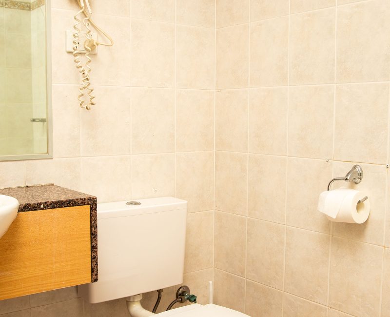 Nandewar Motor Inn's bathroom area with walls tiled in large, square, light beige or pale pink marbled tiles.