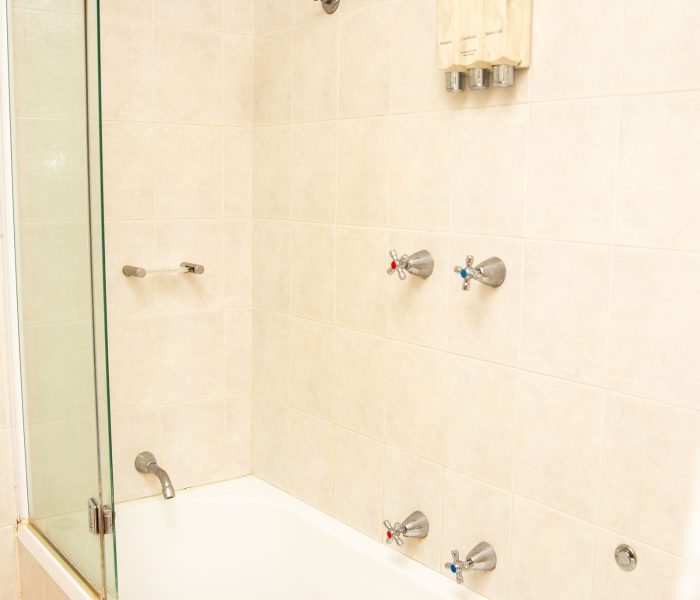 A bathroom area with walls covered in large, square, light beige or pale pink marbled tiles.