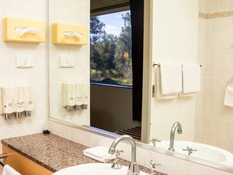 A bathroom vanity with a white drop-in sink and chrome fixtures, set into a counter with a speckled brown and white granite-look top.