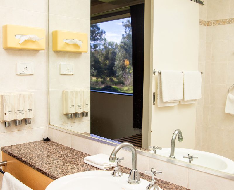 A bathroom vanity with a white drop-in sink and chrome fixtures, set into a counter with a speckled brown and white granite-look top.