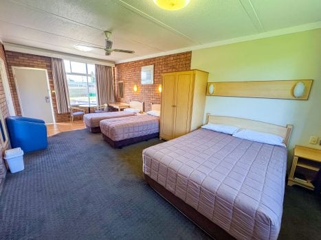 A wide-angle view of Nandewar Motor Inn room with three single or double beds.
