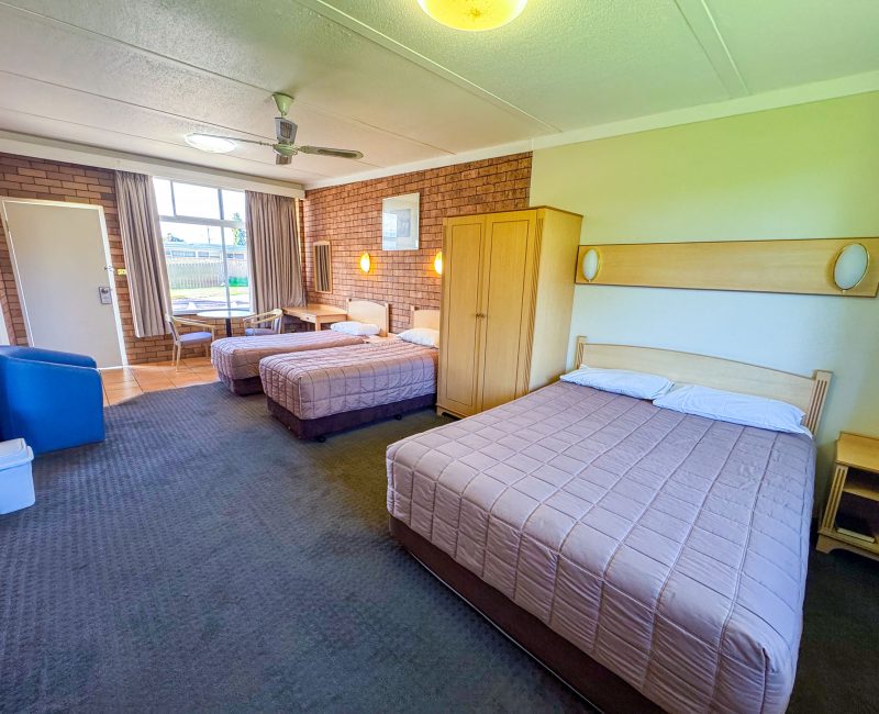 A wide-angle view of Nandewar Motor Inn room with three single or double beds.