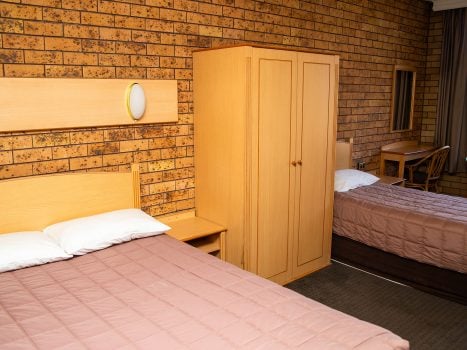 Nandewar Motor Inn's room featuring two beds: a double or queen-sized bed in the foreground and a single bed in the background.