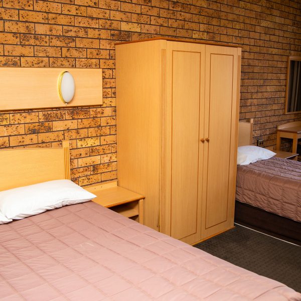 Nandewar Motor Inn's room featuring two beds: a double or queen-sized bed in the foreground and a single bed in the background.