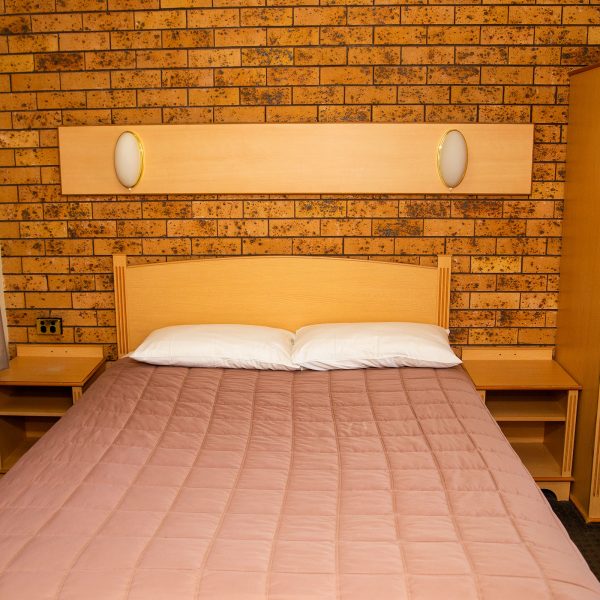 A straight-on view of the bed and storage area in a Nandewar Motor Inn's room.
