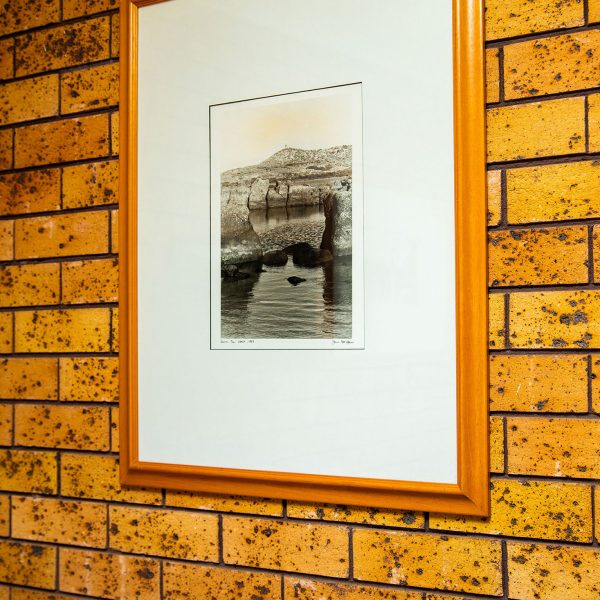 A framed picture hanging on a distinctive brick wall of Nandewar Motor Inn