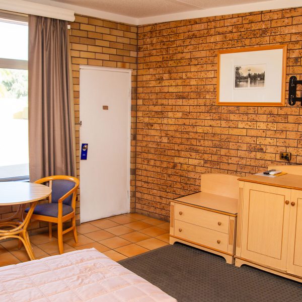 Comfortable Nandewar Motor Inn room with wooden furniture and TV.