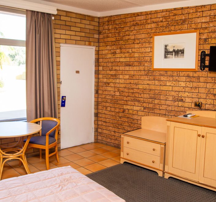 Comfortable Nandewar Motor Inn room with wooden furniture and TV.