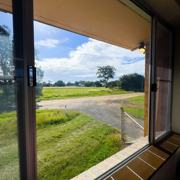 An expansive, rural landscape seen through a large window or sliding glass door.