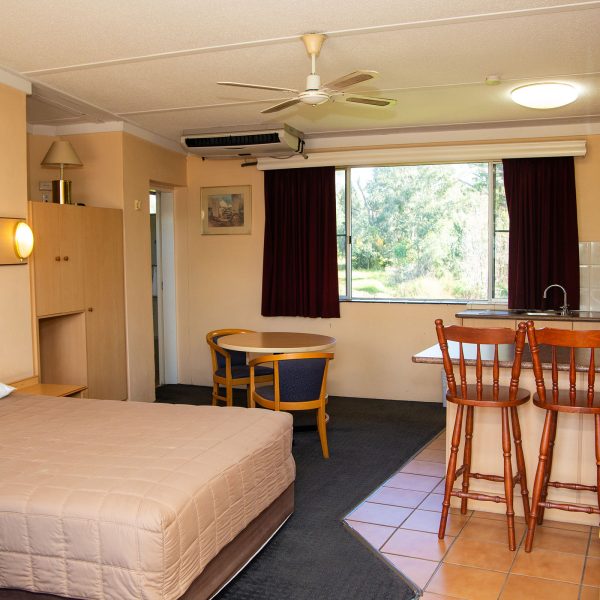 Nandewar Motor Inn room that is divided into sleeping, dining, and kitchenette areas.