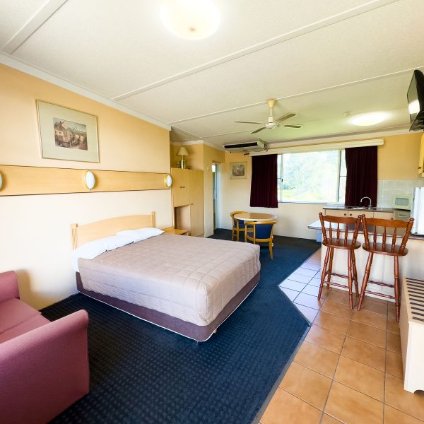 The full interior of Nandewar Motor Inn room that is divided into sleeping, lounge, and kitchenette areas.