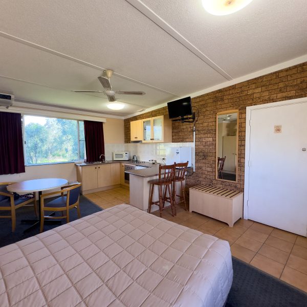 The full interior of Nandewar Motor Inn's room that is equipped with a kitchenette and multiple living areas.