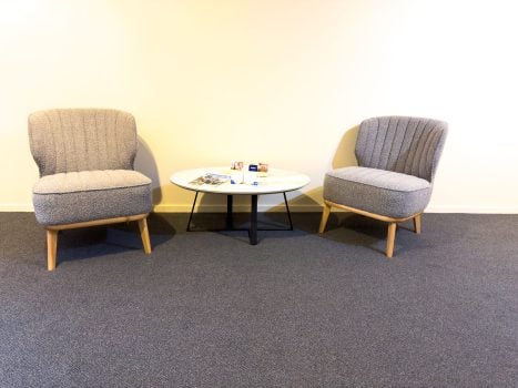 A minimalist seating area with two contemporary armchairs upholstered in a textured gray fabric.