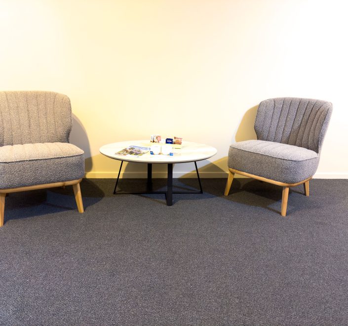 A minimalist seating area with two contemporary armchairs upholstered in a textured gray fabric.