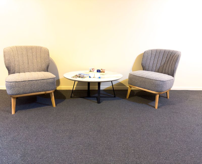 A minimalist seating area with two contemporary armchairs upholstered in a textured gray fabric.