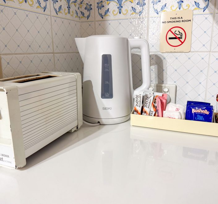 A close-up of a brightly lit white countertop holding a small selection of appliances and amenities.