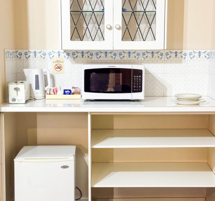 A small kitchenette area with light wood-toned base cabinets and a white countertop.
