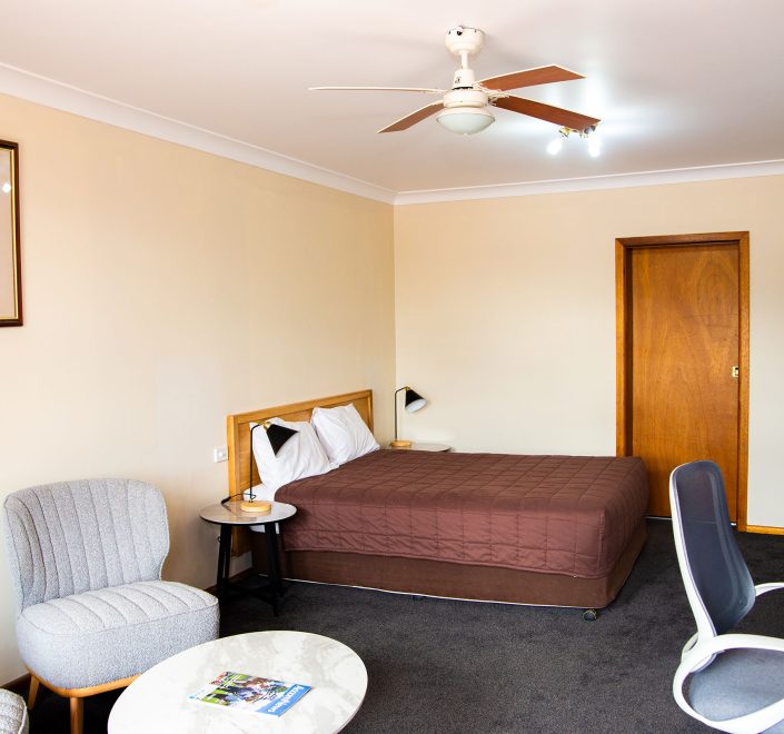 A wide view of Nandewar Motor Inn's room with light beige walls and dark gray carpet.